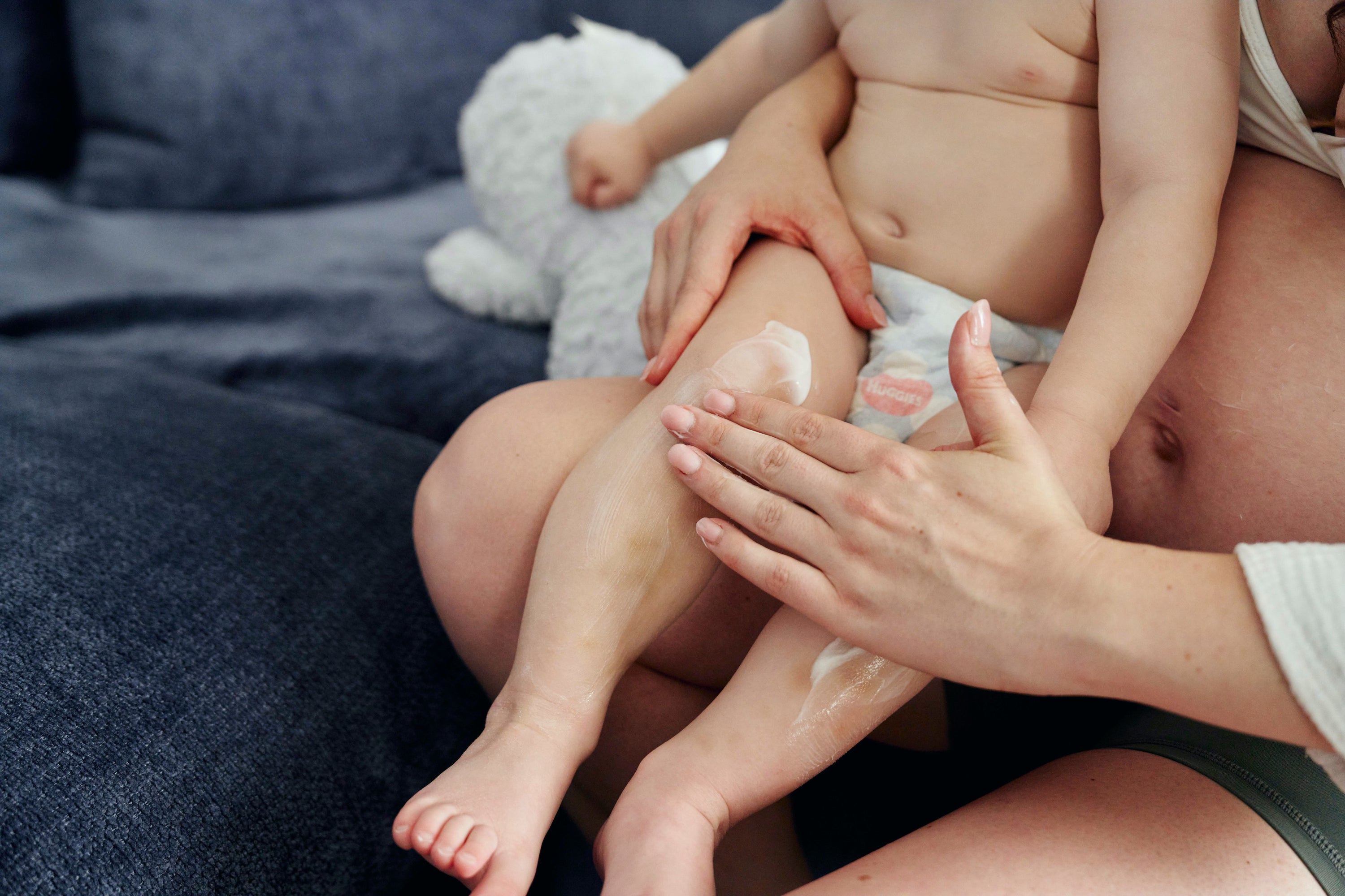 moisturiser being rubbed into baby leg sitting on mums lab